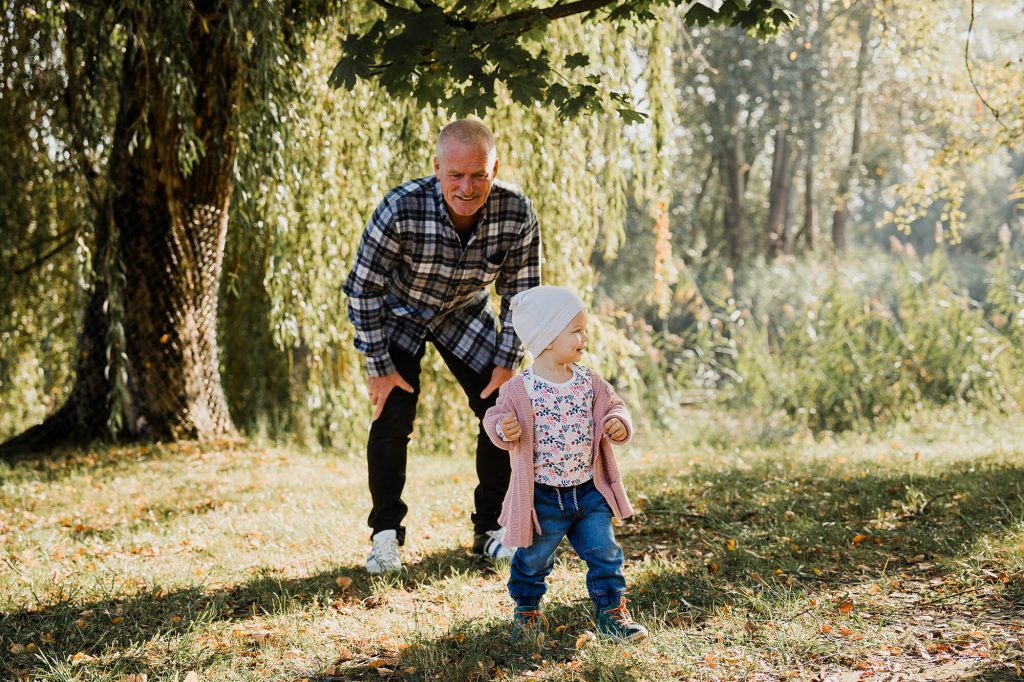 Großvater spielt mit Enkeltochter auf einer Wiese.